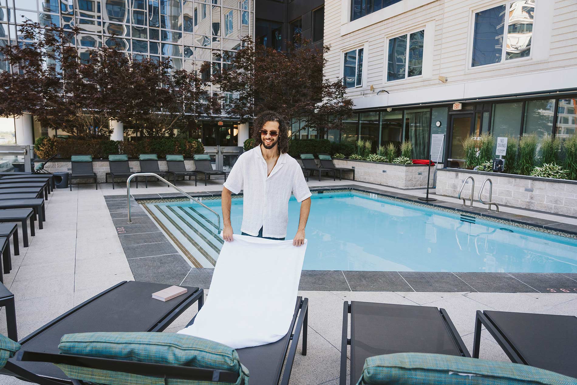 100 Pier 4 man puts towels out on lounge chair by pool
