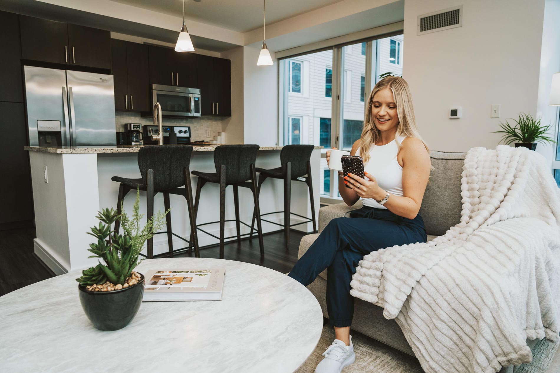 100 Pier 4 man woman sits in living room with phone and coffee