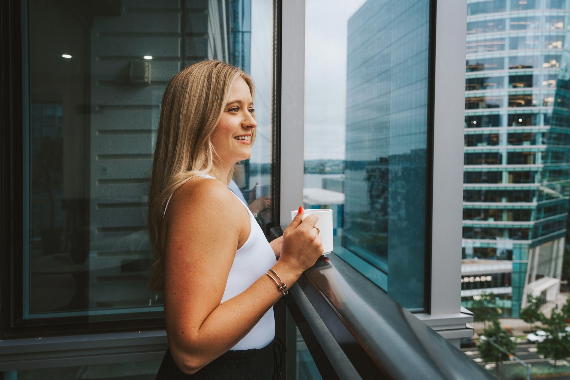 100 Pier 4 woman stands on an apartment patio with coffee