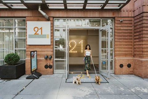 Happy woman walking two dogs outside of 21 Chelsea