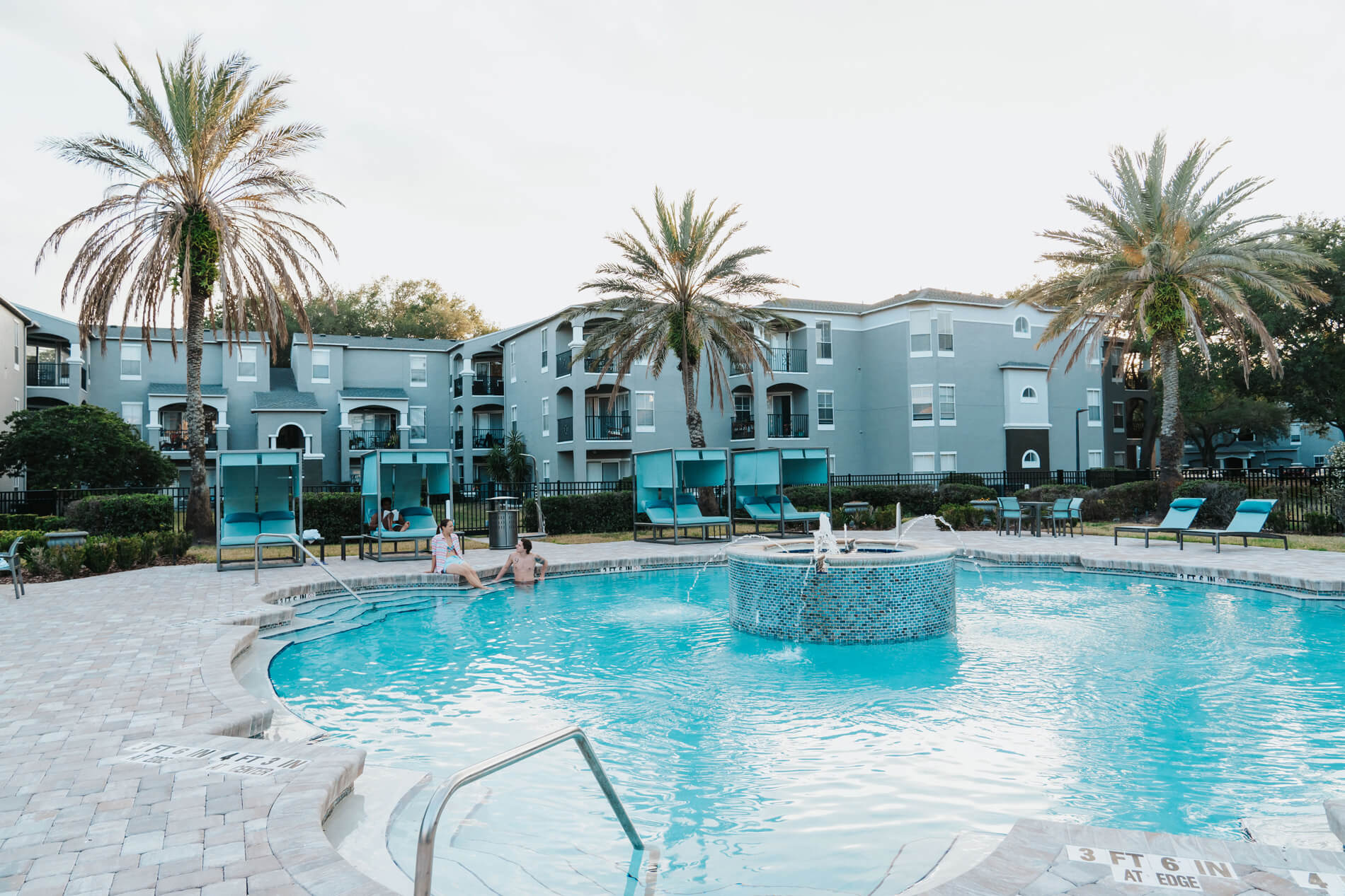 Arbors At Maitland three people sit by pool