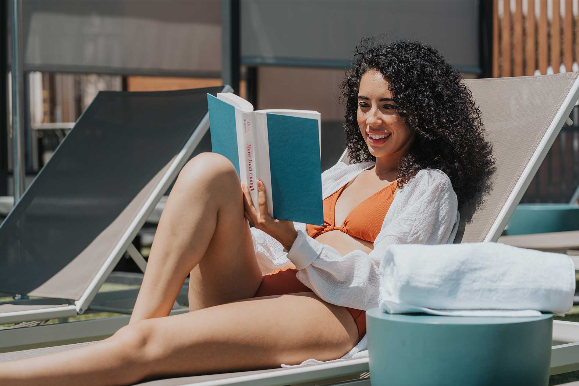 Woman relaxing beside the swimming pool at Avena apartments in Menifee, California