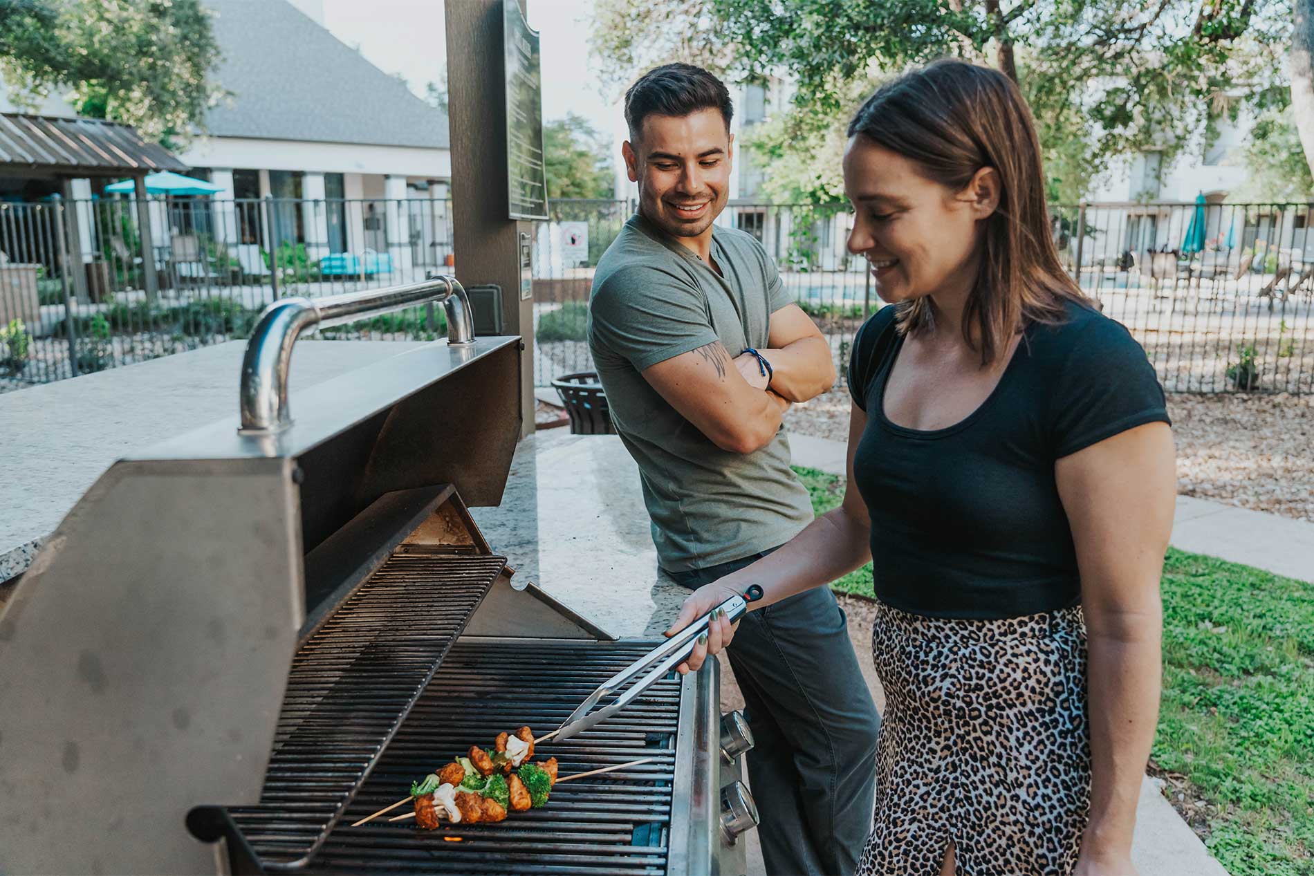 Couple preparing a meal at the outdoor grilling area at Avena apartments in Menifee