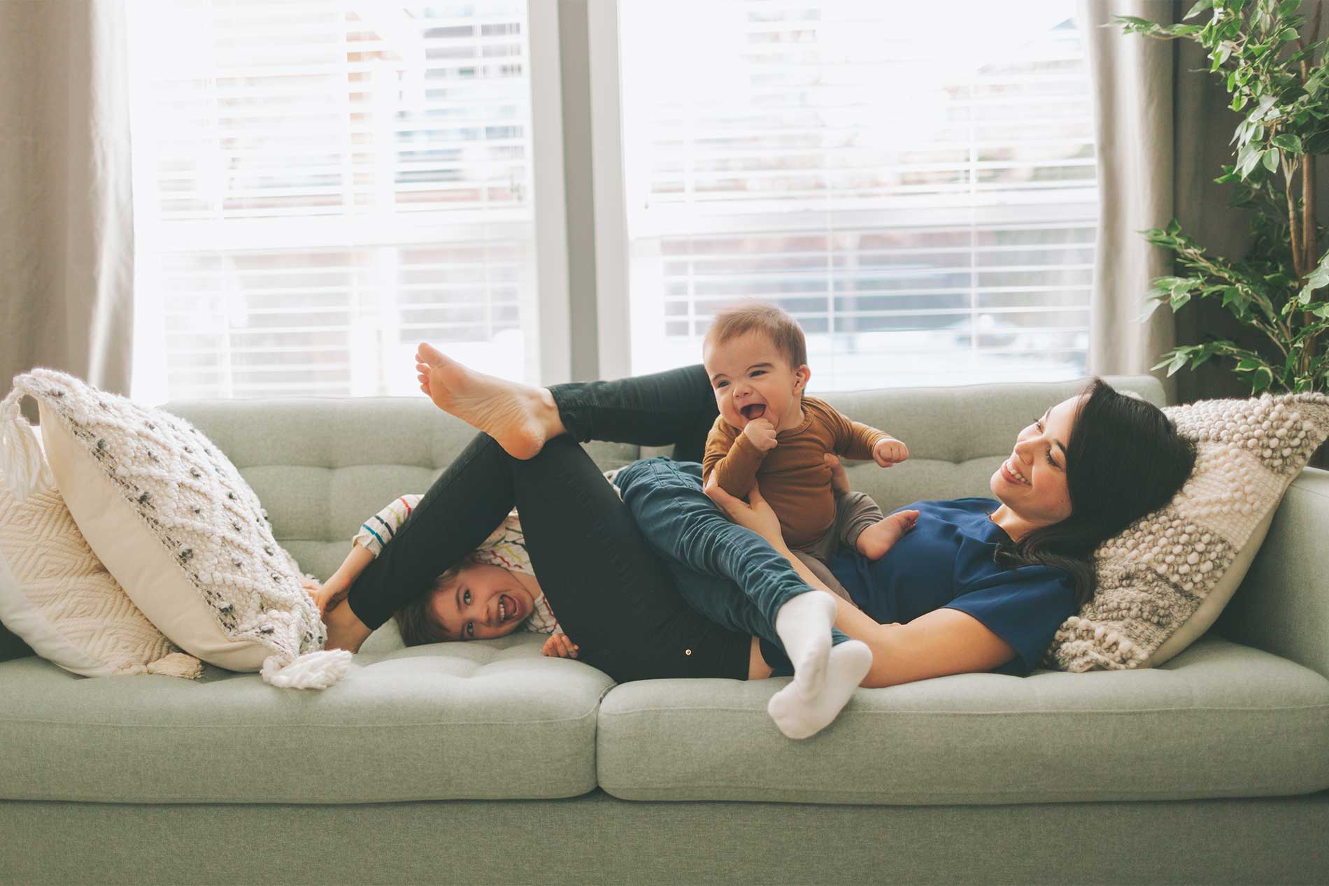 Mother relaxing with her children in a living room at Avena apartments in Menifee, CA