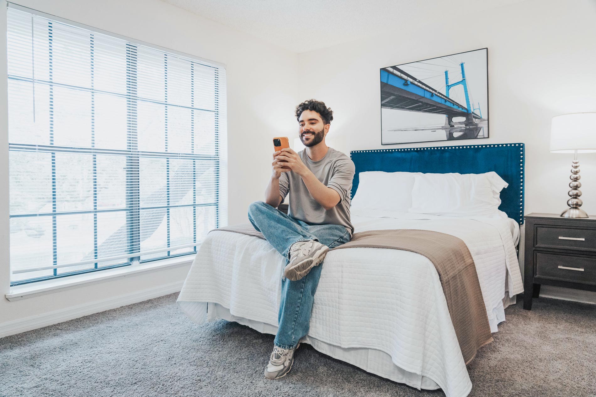 Cambridge Woods man plays on phone on a bed