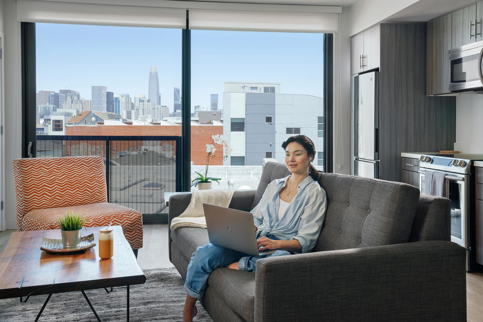 HQ woman works on laptop in staged living room