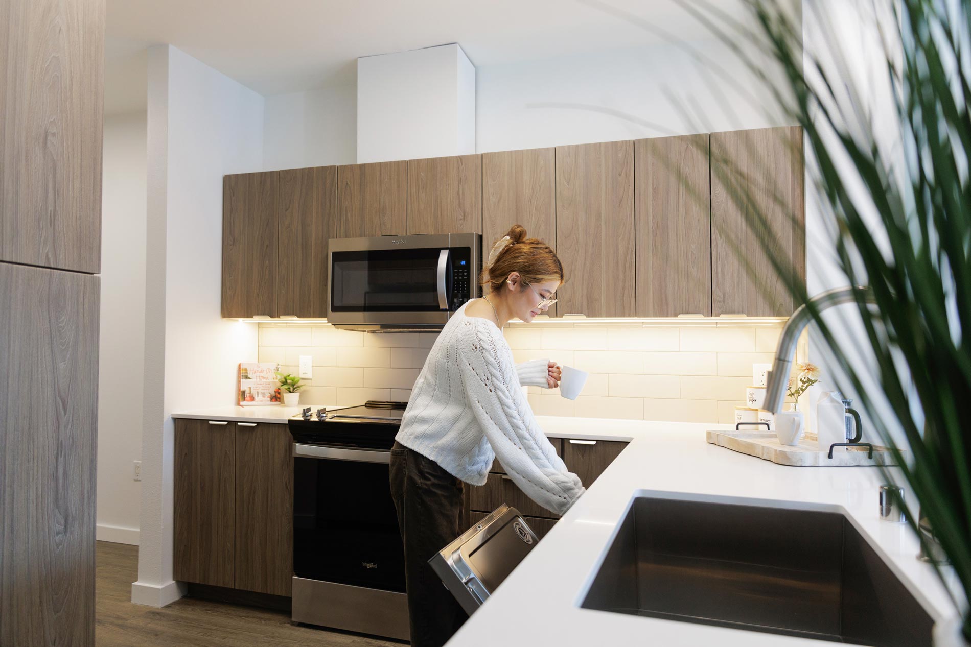 Island Square woman puts something in kitchen dishwasher