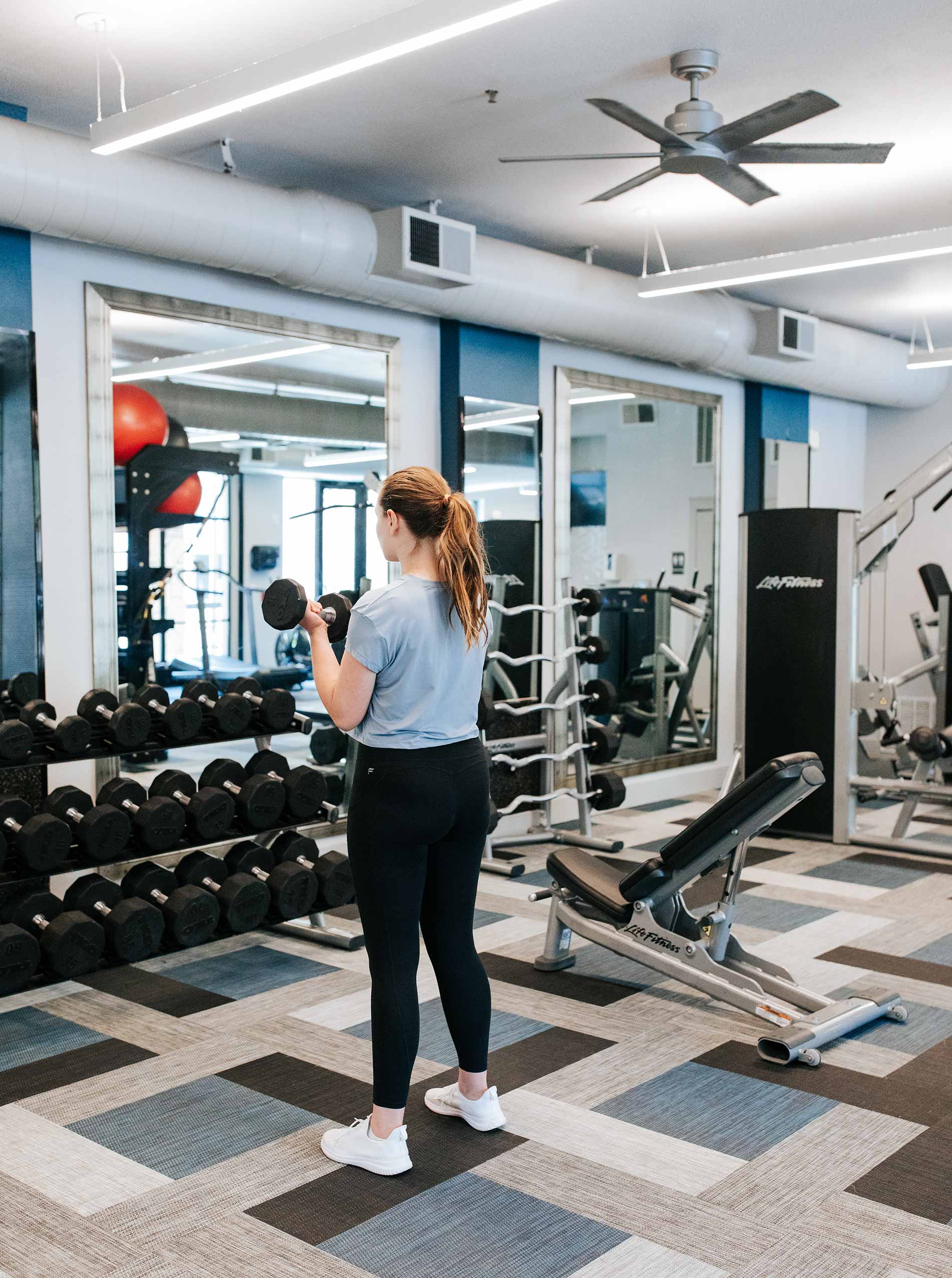 Legacy Village woman lifts weights in fitness center