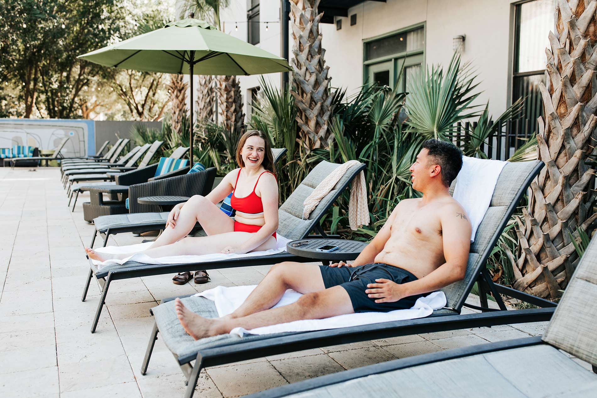 Legacy Village couple sits in lounge chairs by the pool