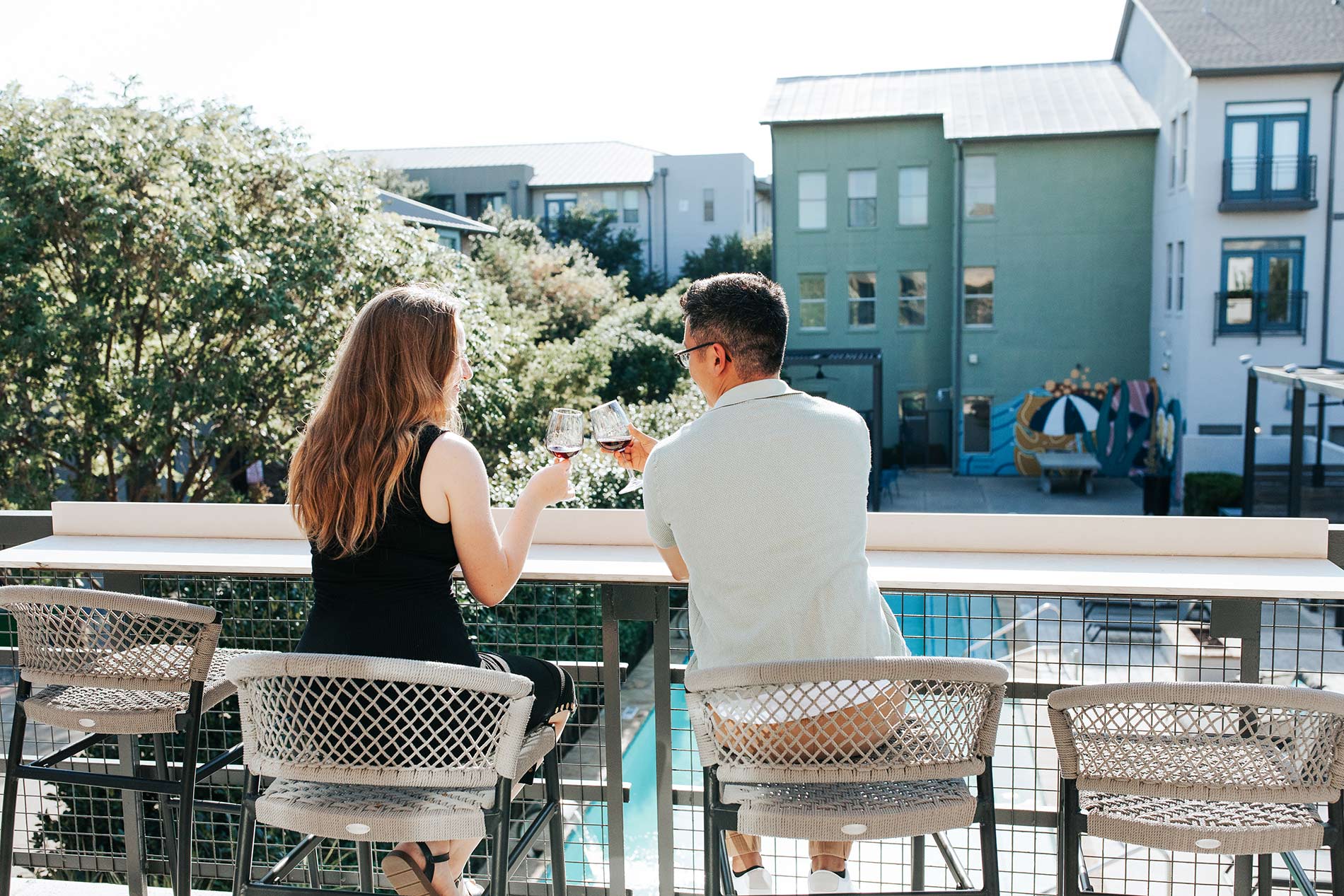 Legacy Village couple drinks wine on the terrace overlooking the pool