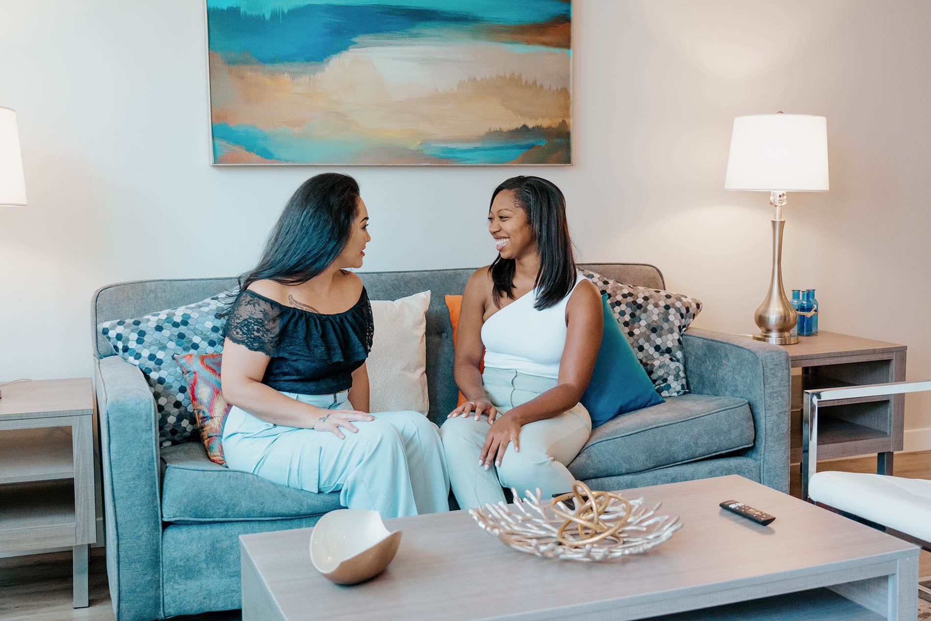 Two women sit on a living room couch