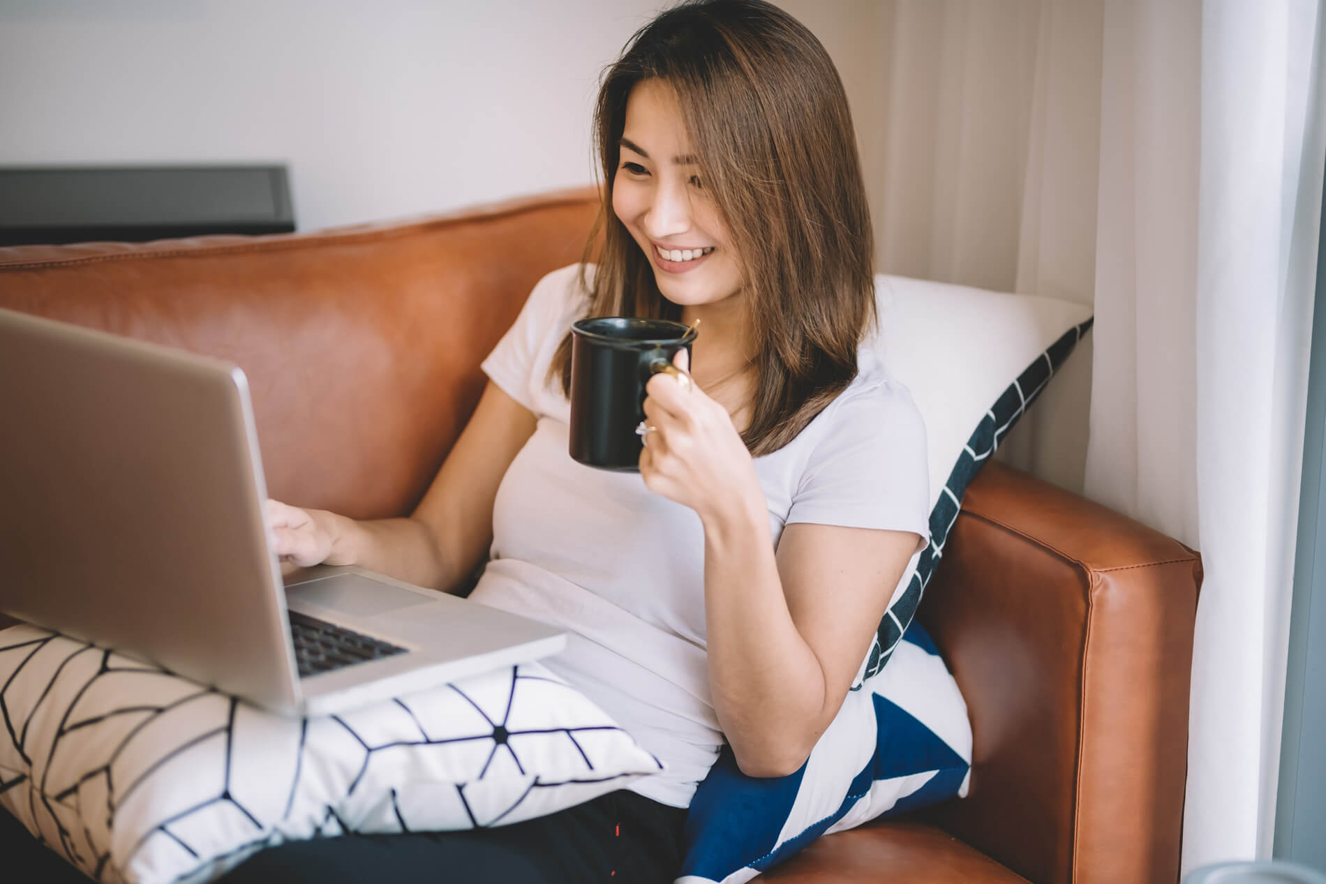 Woman drinking coffee looking at her laptop