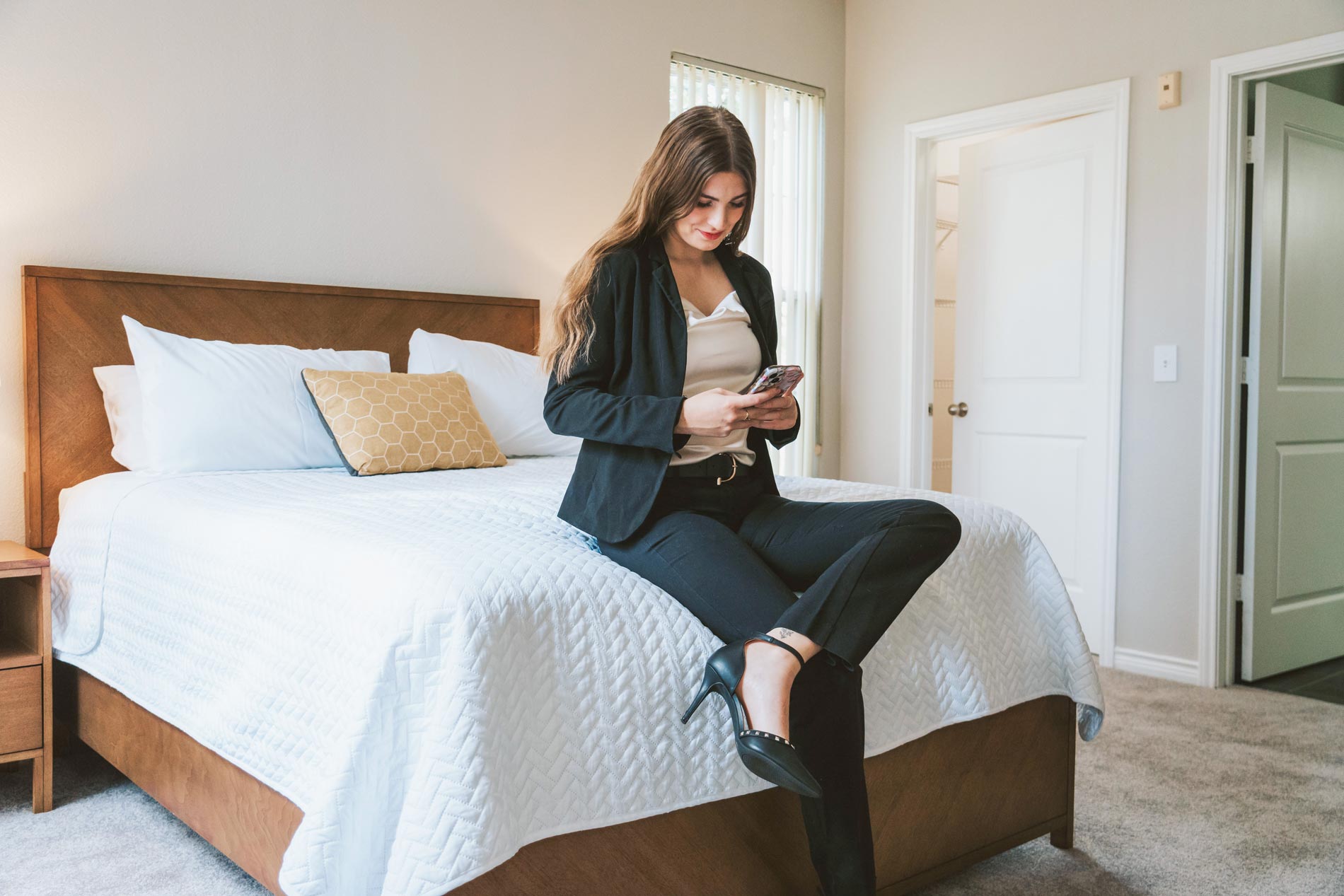 Ridge at Blue Hills woman sits on bed with phone