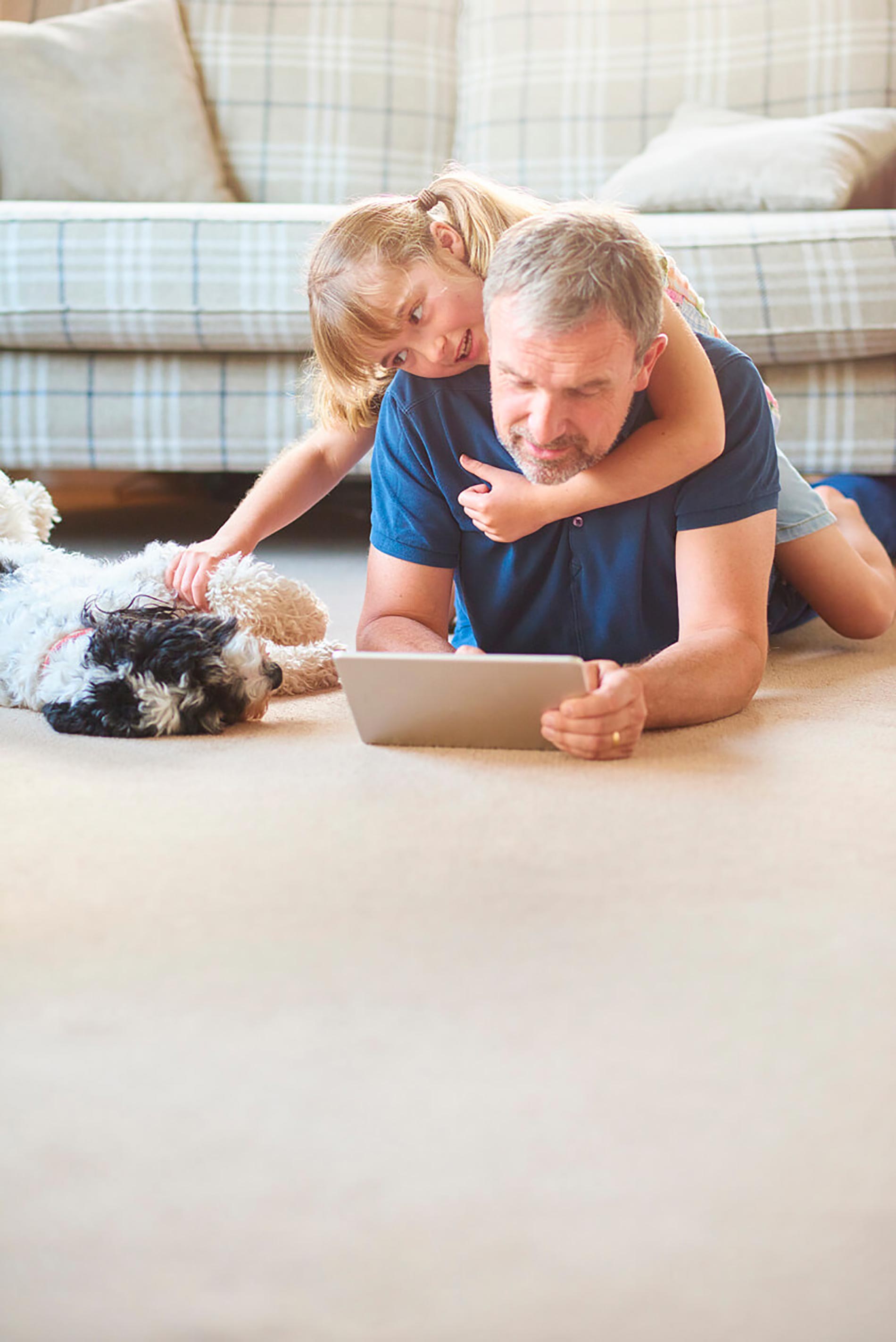 Father and daughter laying with dog on the floor