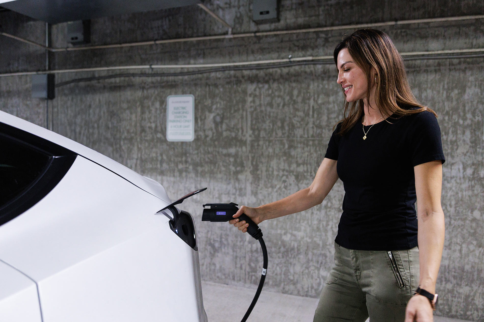 Enclave woman plugs in EV charger