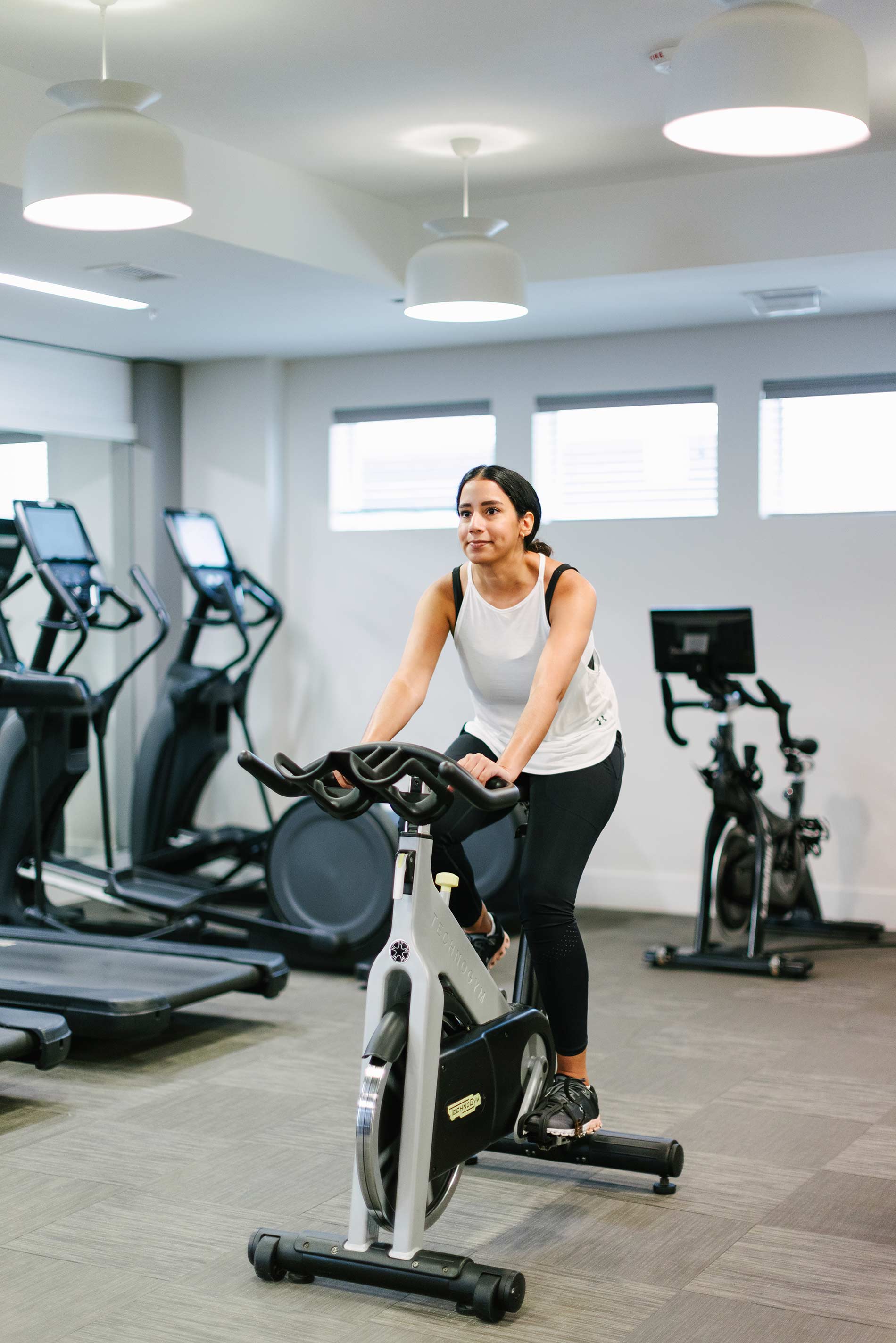 The Enclave woman rides stationary bike in fitness center