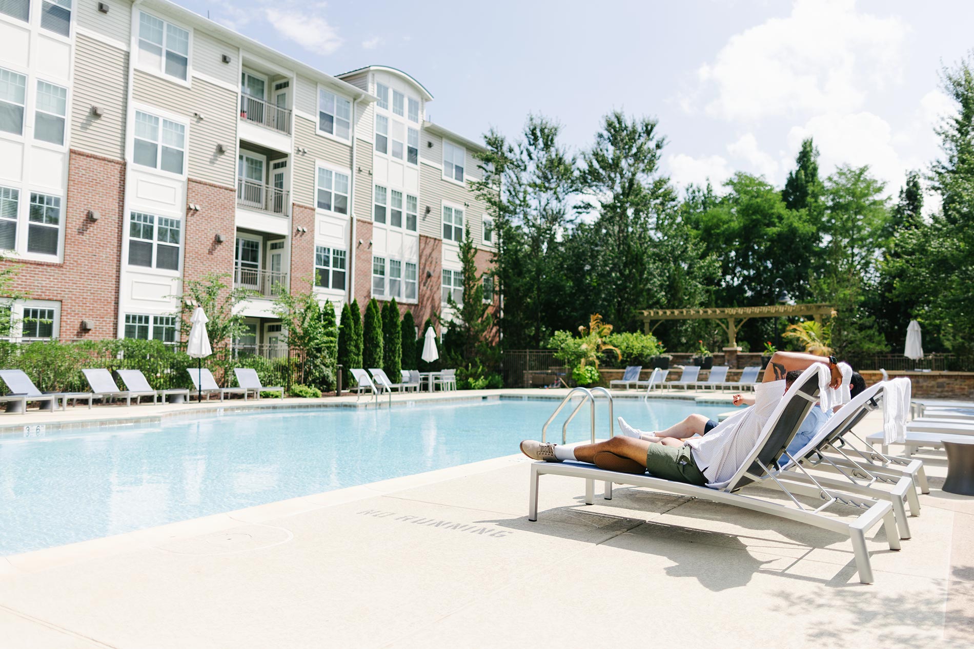 The Enclave people sit in lounge chairs by the pool