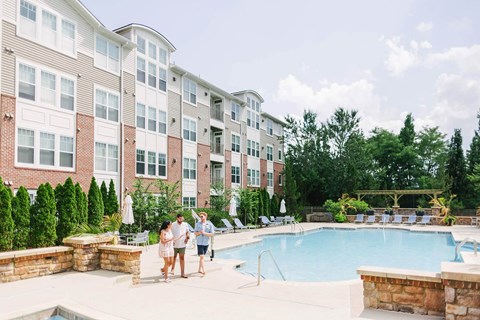 Three people walk by pool at The Enclave apartments in the Woodbridge neighborhood of Washington DC features updated interiors, outdoor amenities and is located in the desirable community of Potomac Club