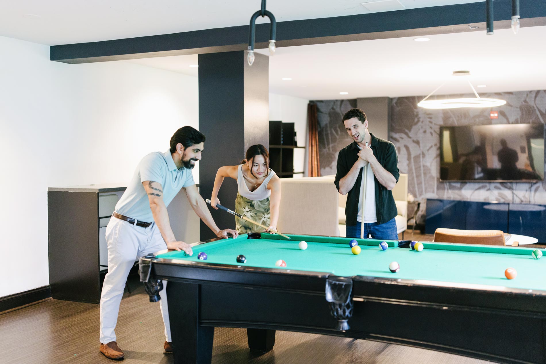 Whitmore apartments three people play a game of pool