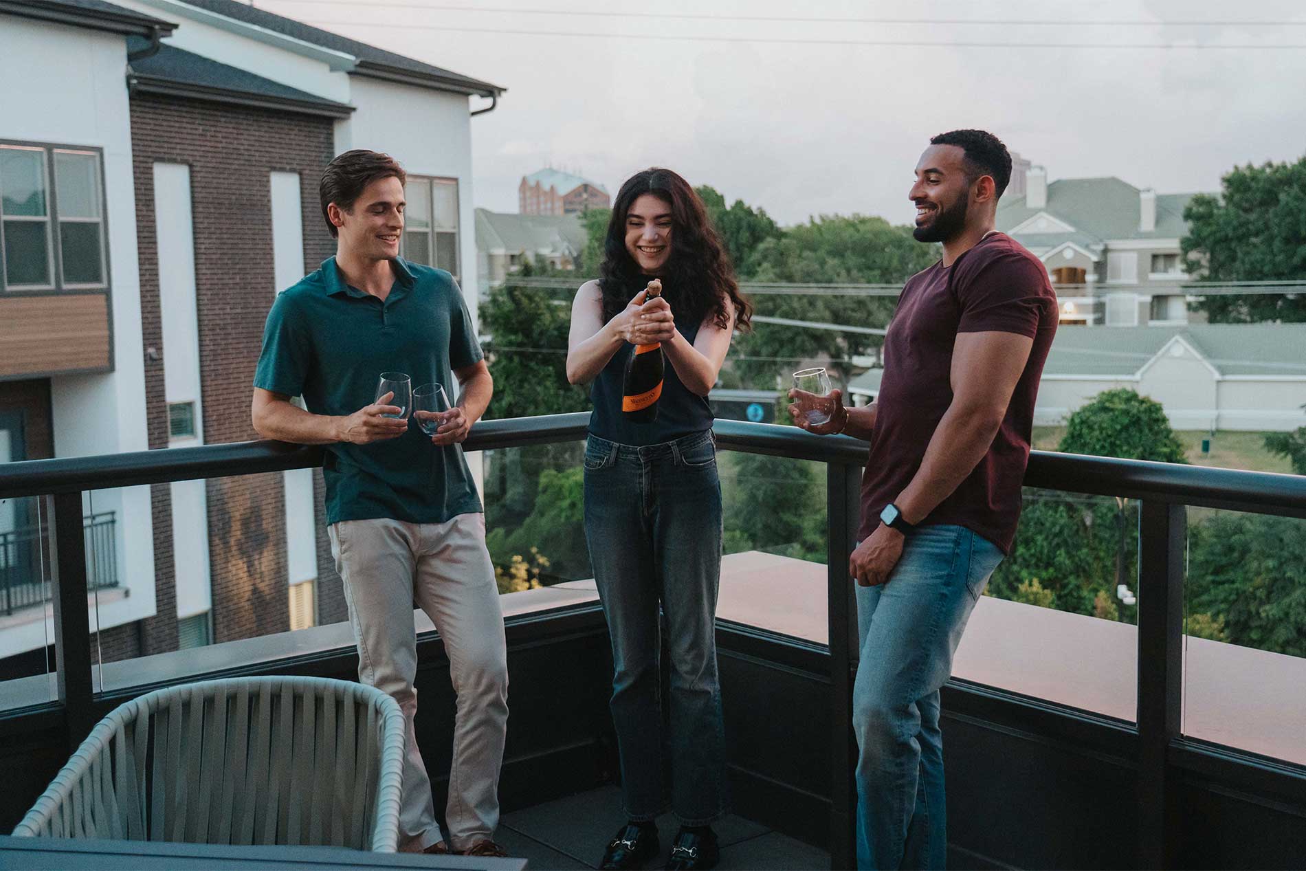 Three young people opening a bottle on a terrace