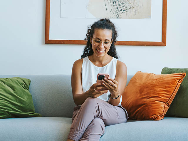 A woman comfortably seated on a couch, using her phone