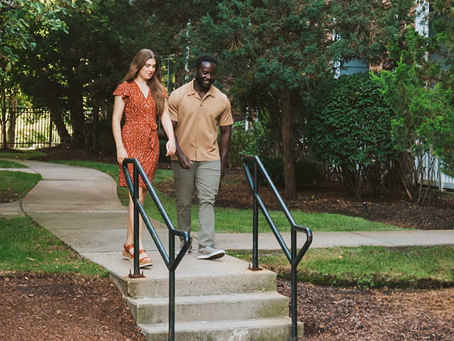 A couple walks hand in hand down the stairs at an apartment community