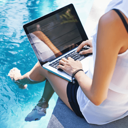 woman sitting with laptop by pool