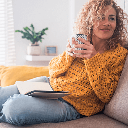 girl on couch with notebook and mug